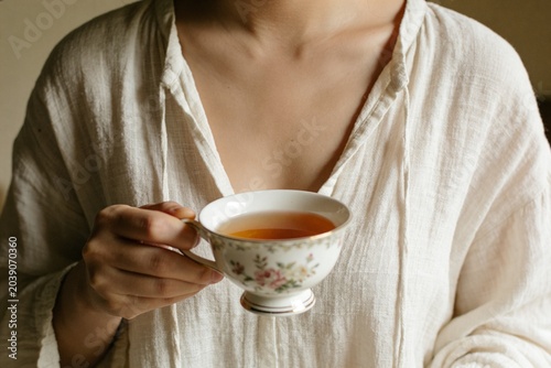 Woman holding a cup of tea. No face.