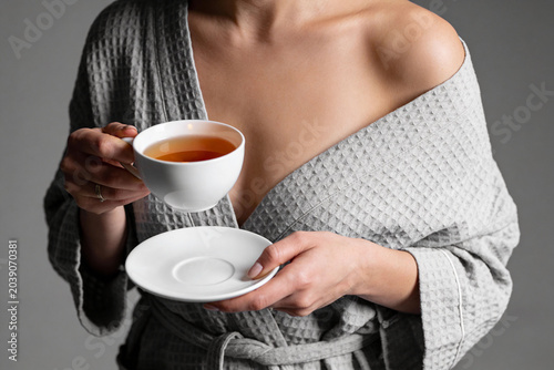 Woman holding a cup of tea. No face.