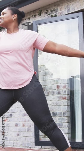 Vertical video: Flowing woman in pink top from prayer to backbend on patio with mat for fitness