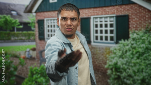 Bild auf Leinwand Man pointing finger with outstretched hand at camera in front of brick building entrance; accusation anger