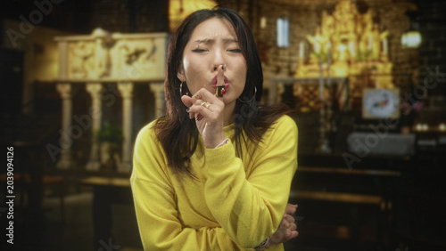 Cuadro en lienzo Woman finger to lips for silence in church building wearing yellow sweater; silence secrecy contemplation