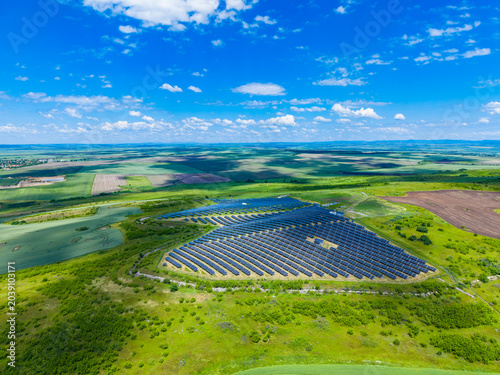 Ecofriendly solar farm. Renewable energy field from above. Sustainable solar panel installation in nature. Aerial view of ecoconscious solar power facility amid greenery