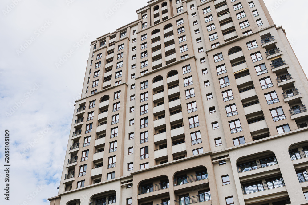 Fototapeta premium Vertical rhythm of apartment tower facade with repeating openings and textured surfaces, conveying ordered urban density and architectural rhythm for design use