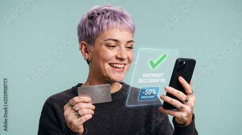 Young happy woman holding credit card and mobile phone making successful online payment and receiving a 50% discount standing on light blue studio background