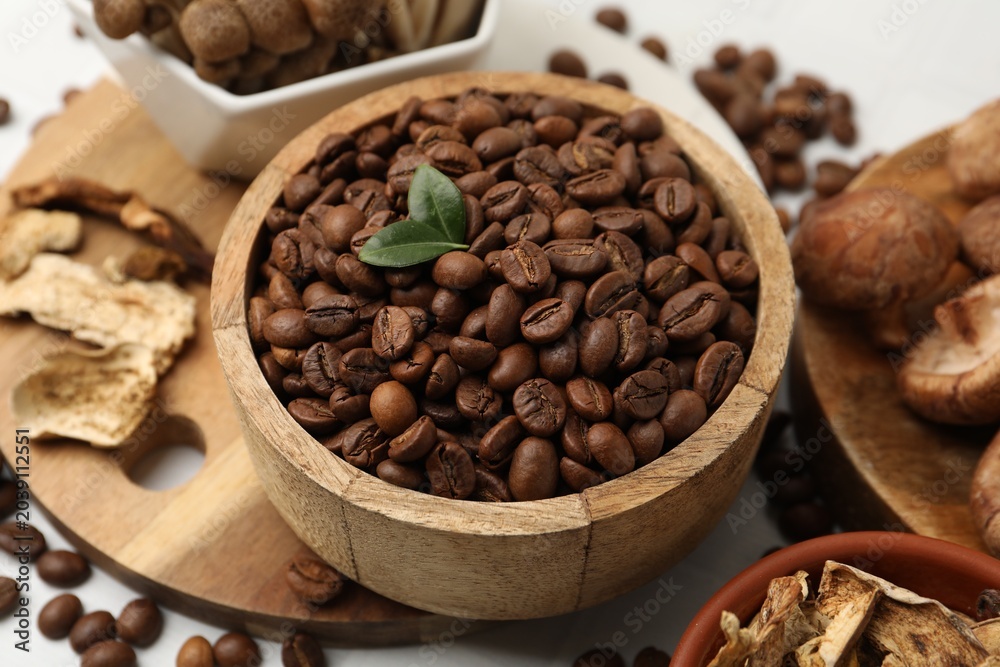 Fototapeta premium Coffee beans and mushrooms on white table, closeup