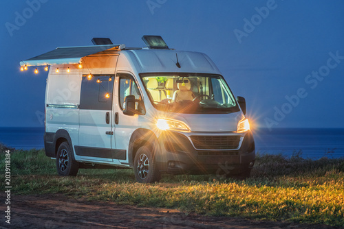 romantic lights in camper van on the cliff on sea side in evening twilight