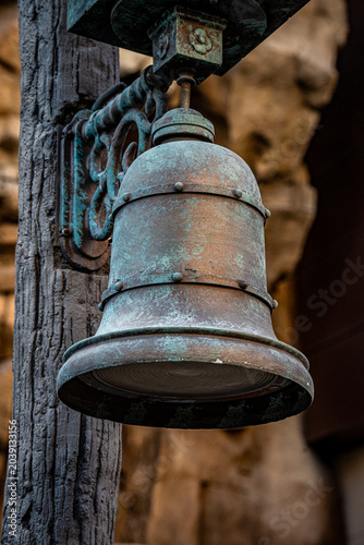 Obraz na plátne Close-up of an old, weathered bronze bell with verdigris patina on a textured wo