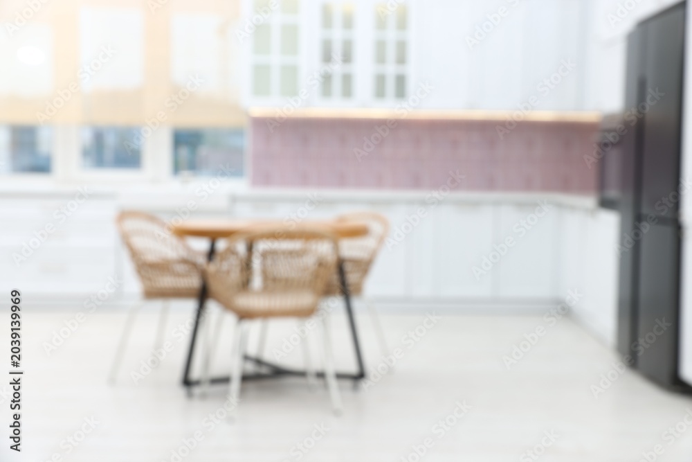 Fototapeta premium Blurred view of stylish kitchen interior with wooden table and chairs