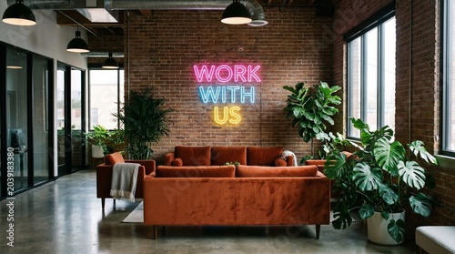 Modern office lounge area with comfortable seating and vibrant neon sign that says 'Work With Us' promoting employment opportunities