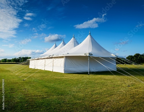 large white tent structure in open field under blue sky