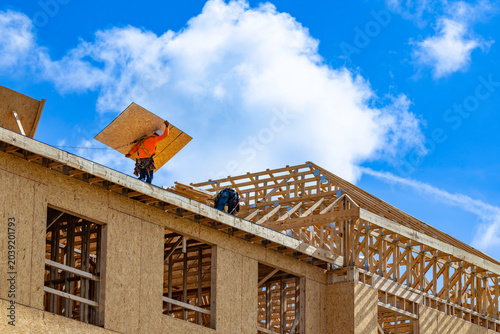 Photography A wide horizontal low-angle view of construction workers wearing safety harnesse