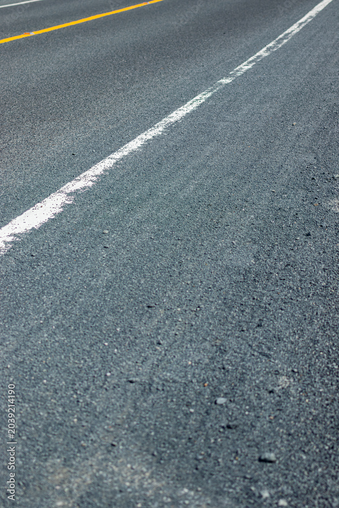Fototapeta premium Close up view of an asphalt road surface with a solid white painted line guiding perspective.