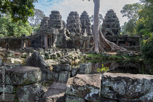 Banteay Kdei Temple, Angkor Wat, Cambodia, where ancient stone structures are entwined with massive tree roots, showcasing the power of nature reclaiming historical architecture.