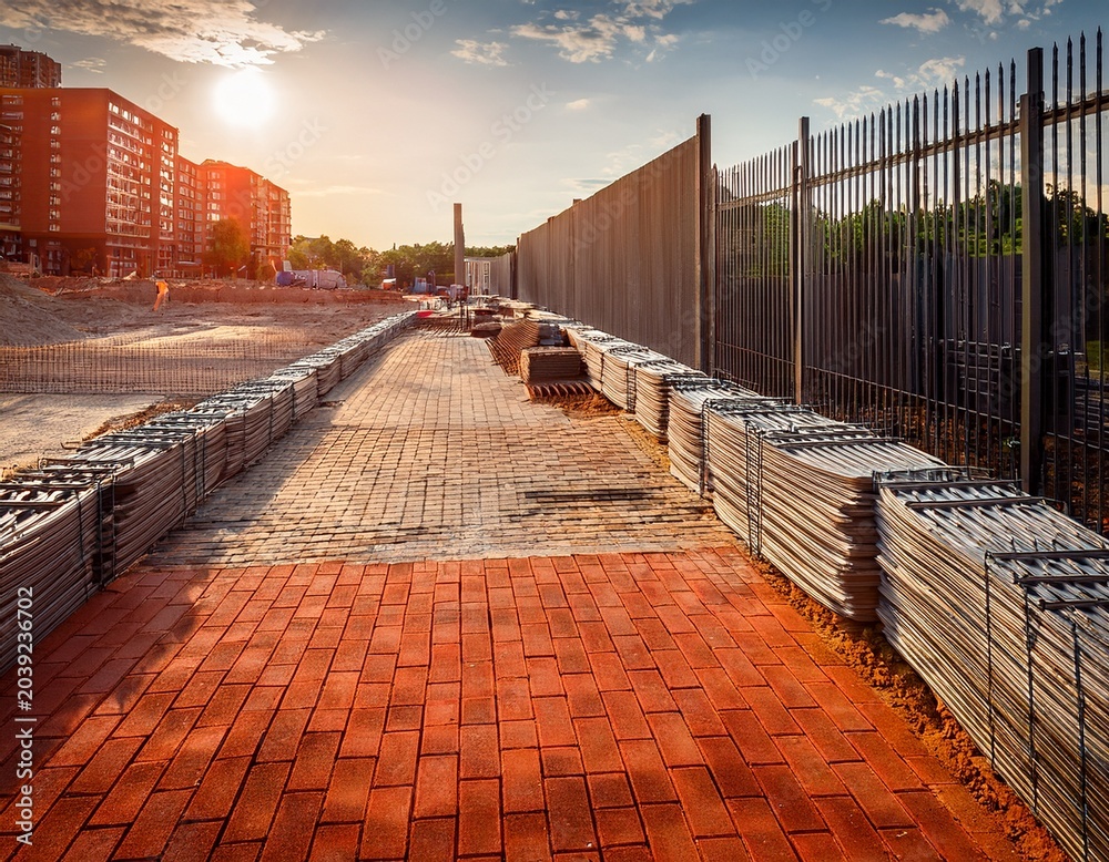Obraz premium a construction site with a sidewalk being built using bricks and a metal fence