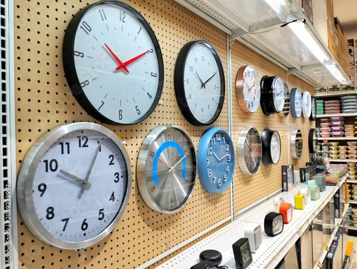 Collection of round wall clocks with different designs hanging on a pegboard wall. time is money concept