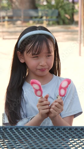Young Asian Girl Enjoying Pink Butterfly Popsicles in Sunny Outdoor Park