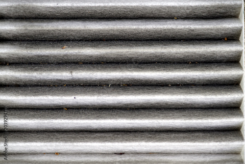 Used automotive cabin air filter clogged with dust and dirt, close-up texture showing the need for replacement and regular vehicle maintenance to improve air quality and passenger health.