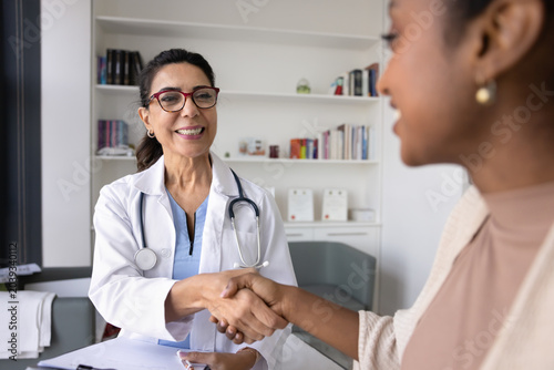 Foto Cheerful middle aged physician shaking hands with young Black patient, giving respect, support, confidence, empathy