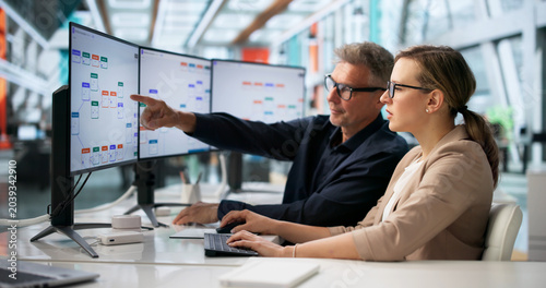 Konstfotografi Two Business Professionals Discuss Automated Workflow System Improvements