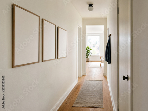 Row of three blank frames mockup for wall art display in narrow apartment hallway with natural light and copy space
