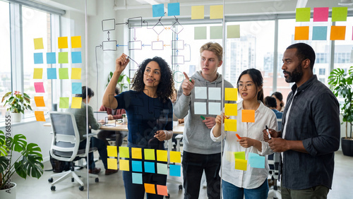 Diverse professional team brainstorming business strategy using sticky notes on a glass wall