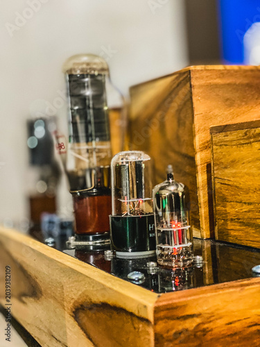 Obraz na plátně Close-up shot of vintage vacuum tubes glowing faintly on a high-end audio amplifier with a premium polished wooden chassis