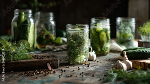 Pickling cucumbers in glass jars with fresh herbs