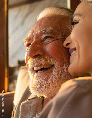 Smiling older father and adult daughter laughing together indoors at sunset