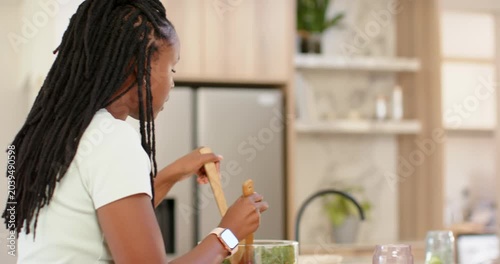 African American friends joining woman tossing salad in bowl at island, plating, tasting meal