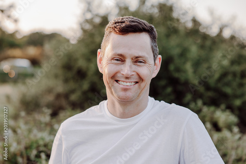 Smiling man portrait outdoors in warm natural garden light