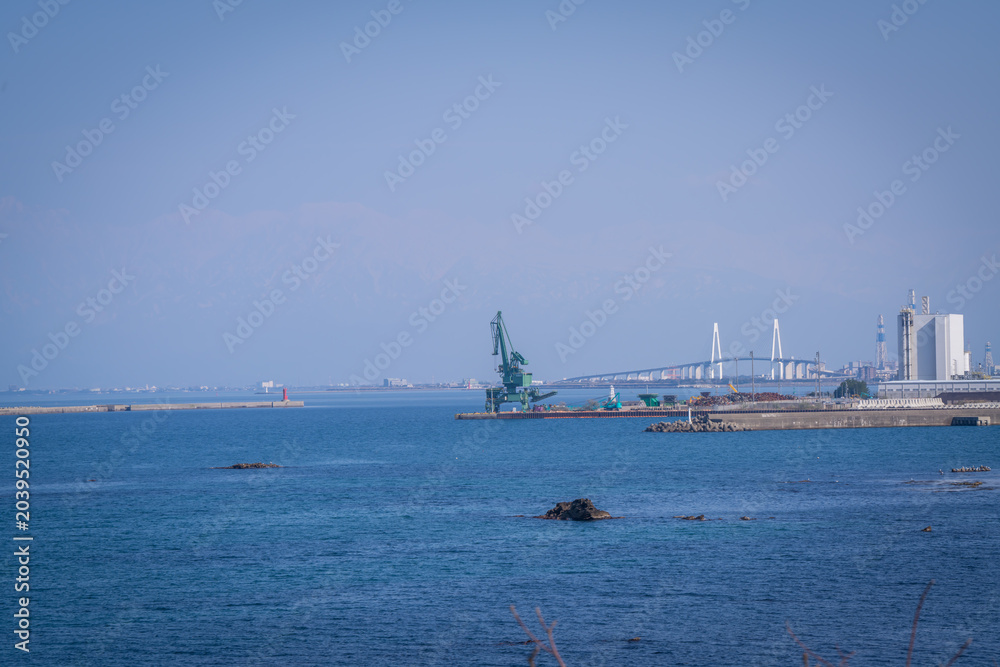 Obraz premium beautiful landscape of industrial factory , shinminato bridge an Japan alps background is amazing view at Amaharashi Coast Toyama Japan