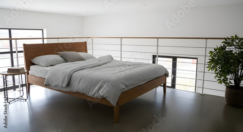 Modern light wood bed frame with grey bedding in a bright minimalist bedroom interior