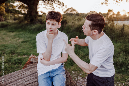 Fényképezés Father joking with unimpressed teenage son in outdoor family portrait