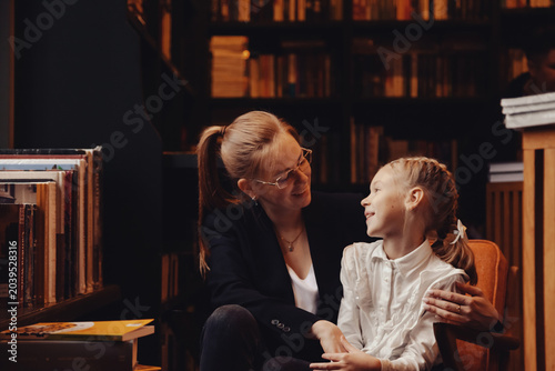 Foto Mom and daughter share a joyful moment in a library, surrounded by books