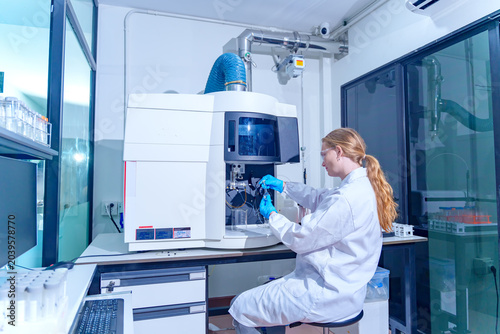 Scientist in lab coat works with advanced analytical instrument in modern research laboratory