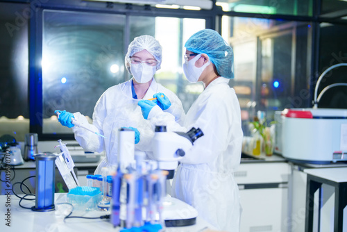 Scientists in protective gear collaborate on research in a modern laboratory setting