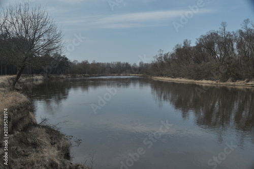 Calm river scene surrounded by trees in early spring offers a serene landscape for nature lovers to enjoy