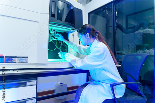 Фотография Scientist in lab coat working with advanced analytical equipment under blue ligh