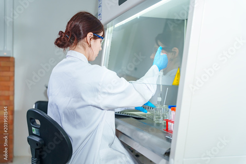 Фотография Scientist in protective gear working with samples inside a sterile laboratory fu