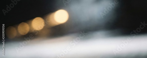 Abstract background featuring soft focus glowing golden circular light orbs floating in dark space with blurred motion and atmospheric particle effects for design