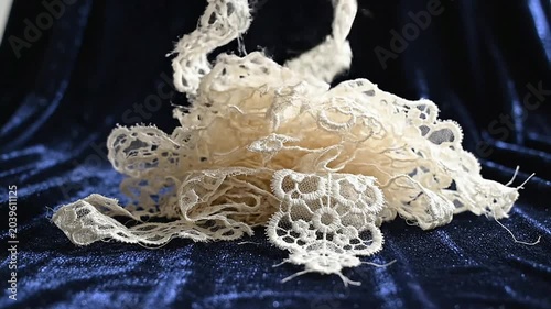 Delicate White Lace Fabric Cascading Elegantly Over Rich Blue Velvet Background Ideal for Fashion and Crafting Projects