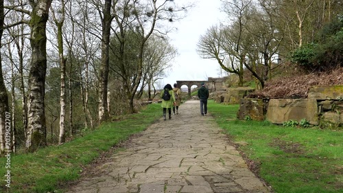 Group of three people walking slowly at Rivington gardens, Northwest England, springtime, rear view.

