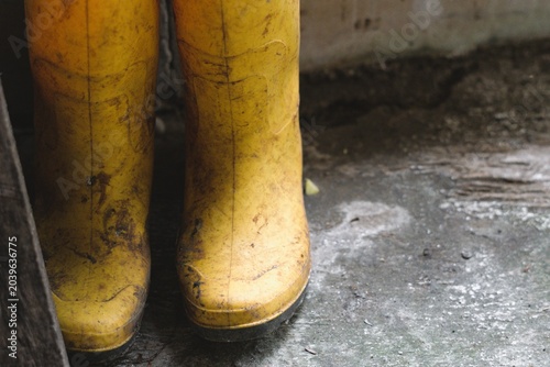dirty yellow rubber boots on a gritty concrete floor