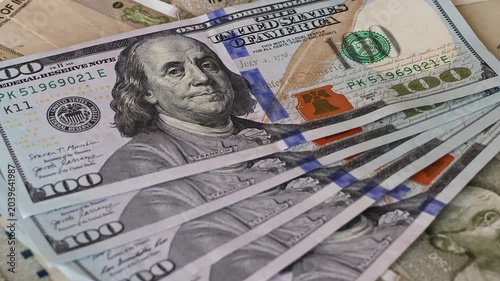 100 american dollar banknotes (USD) are placed on top of Indian rupees (INR). A hand places currency over scattered 500 bills. Concept of exchange rate, global finance, and international economy.