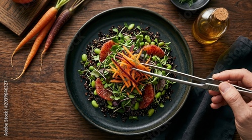 Hand garnishing healthy quinoa salad with fresh carrots