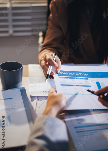 The businesswoman is using a white calculator to check company financial information, she is checking company financial information from the documents provided by the finance department.