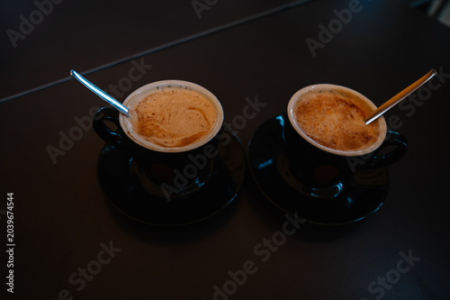 Obraz na płótnie Two steaming cappuccinos rest on dark saucers