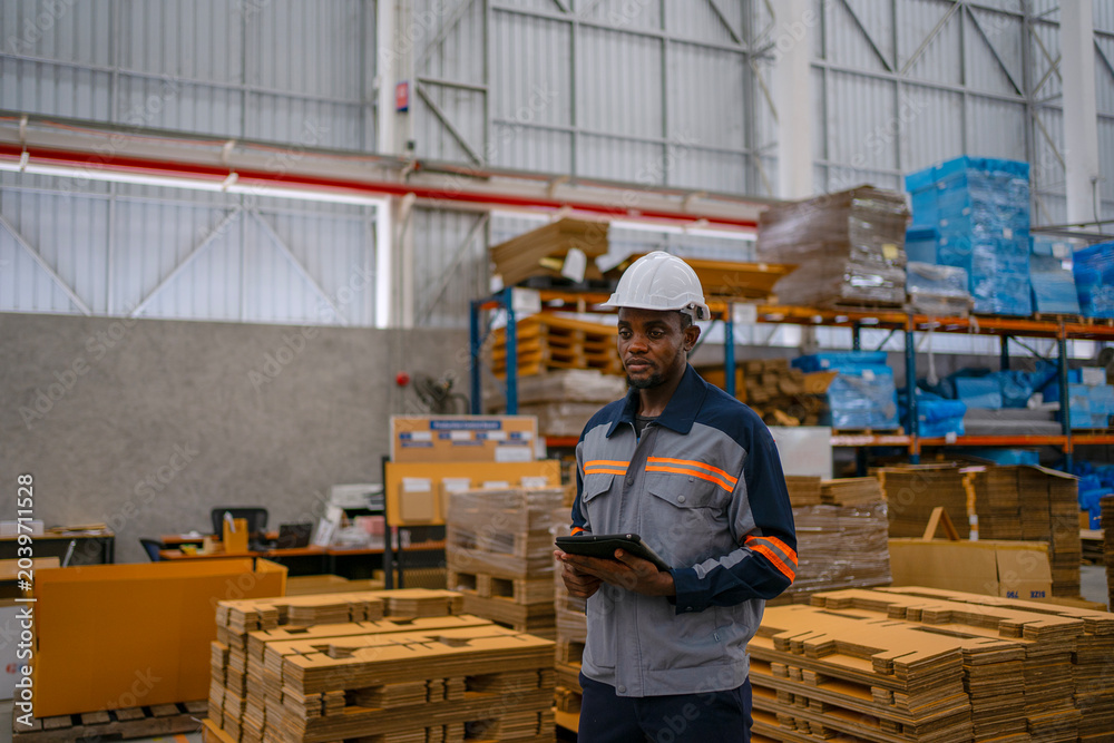 Fototapeta premium Black Factory Worker Using Digital Tablet in Cardboard Warehouse