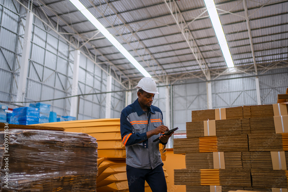 Fototapeta premium Black Factory Worker Using Digital Tablet in Cardboard Warehouse