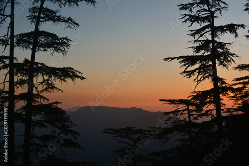 Fotografija Glowing orange and golden colors of a sunset fill the sky, framed by the dark, i